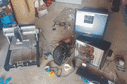 Pixelated photo of a home-built CNC mill wired to an open computer on a workshop floor
