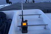 Pixelated photo of a handheld radio standing on the deck of a sailing yacht