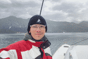 Pixelated selfie of Piotr on the deck of a yacht in the Bay of Kotor, with mountains behind